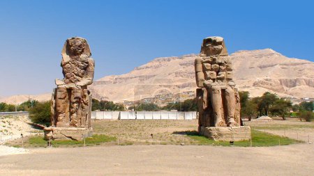Téléchargez les photos : The Colossi of Memnon are two gigantic statues of Amenophis III located on the west bank of the Nile, near Luxor (Egypt). The statues, built 3,400 years ago, show the very peaceful pharaoh with his hands on his knees, gazing at the rising sun. - en image libre de droit