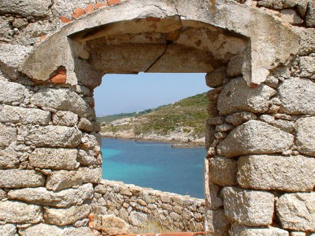Foto de Vista del mar Mediterráneo a través de una ventana de piedra abierta en las murallas de la fortaleza en la península de Revellata, cerca de Calvi en el noroeste de Córcega, apodada la Isla de la Belleza. - Imagen libre de derechos