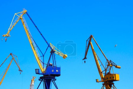 Photo for Beautiful yellow naval cranes, standing out against the azure blue sky of the port of Piraeus, near Athens in Greece - Royalty Free Image