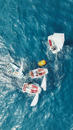 Foto de De arriba hacia abajo tiro de pequeños veleros en una carrera competitiva, redondeando una boya en el mar abierto brillante. - Imagen libre de derechos