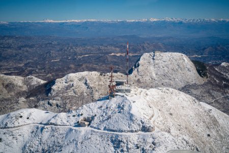 A stunning view of snow-covered mountains with communication towers against a clear blue sky. 