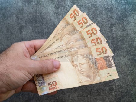 Hand holding fifty reais banknotes. brazilian money.