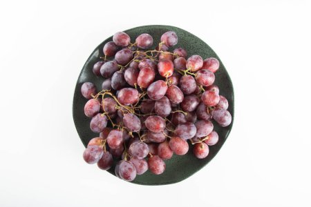 Płyta z fioletowymi winogronami i białym tłem.