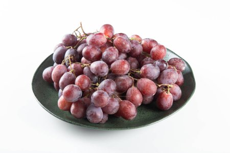 Płyta z fioletowymi winogronami i białym tłem.