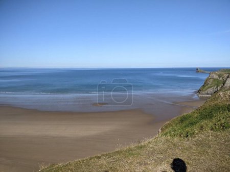Photo for Beach scene with clear sky, ocean waves, and sandy shore. - Royalty Free Image