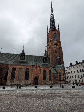 Ein fesselndes Bild, das die gotische Architektur der Backsteinkirche Riddarholm an einem bewölkten Tag in Stockholm einfängt, mit komplizierten Details und imposanten Turmspitzen