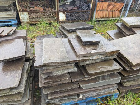Piles of stacked stone slabs in an outdoor construction material yard, showcasing building and landscaping resources.