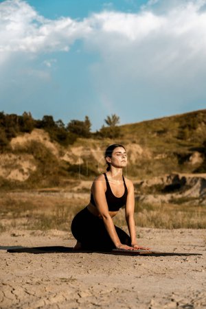 Téléchargez les photos : Femme faisant du yoga et debout sur les ongles dans le désert au coucher du soleil.Le concept de yoga et debout sur les ongles - en image libre de droit