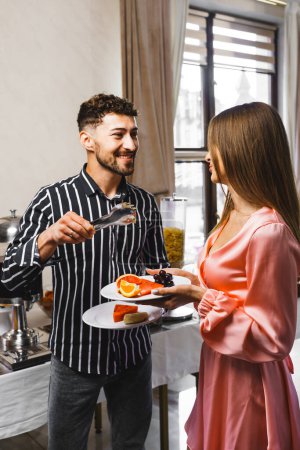 Téléchargez les photos : Un jeune couple amoureux prend son petit déjeuner dans un restaurant d'un hôtel. Le concept de vacances dans un hôtel - en image libre de droit