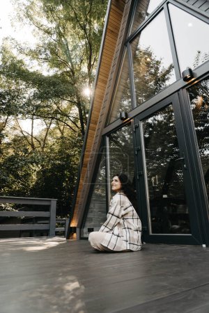 Téléchargez les photos : Une femme se repose et médite dans une maison dans la forêt en automne. Concept de retraite et de méditation - en image libre de droit