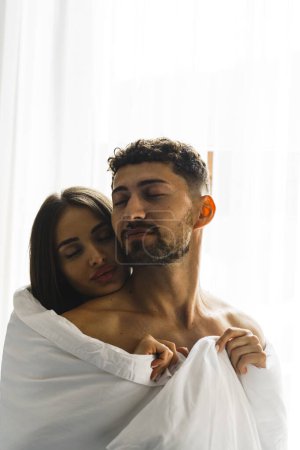 Téléchargez les photos : Couple amoureux posant dans des couvertures dans une chambre d'hôtel dans les montagnes. Concept pour des vacances à la montagne - en image libre de droit