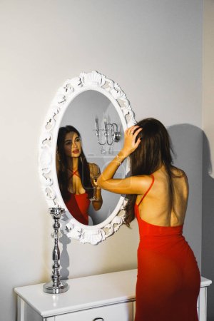 Téléchargez les photos : Femme sexy avec une coupe de champagne dans une robe rouge posant dans une chambre d'hôtel. Concept de vacances coûteux - en image libre de droit