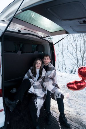 Ein verliebtes Paar hat auf Reisen ein romantisches Date. Ein Mann und eine Frau posieren vor der Kulisse verschneiter Berge und trinken Tee. Reisekonzept