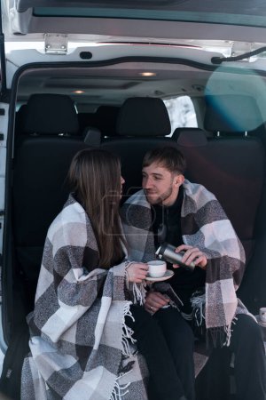 Ein verliebtes Paar hat auf Reisen ein romantisches Date. Ein Mann und eine Frau posieren vor der Kulisse verschneiter Berge und trinken Tee. Reisekonzept