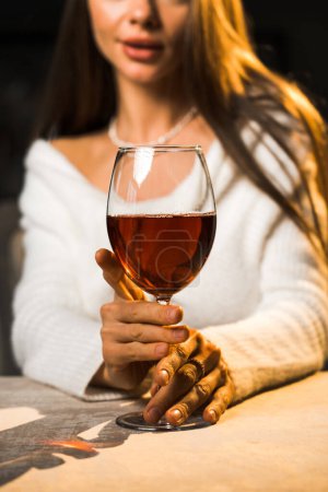 Junge Frau hält ein Glas Wein in der Hand. Frau trinkt Wein in einem Restaurant. Rotweinkonzept