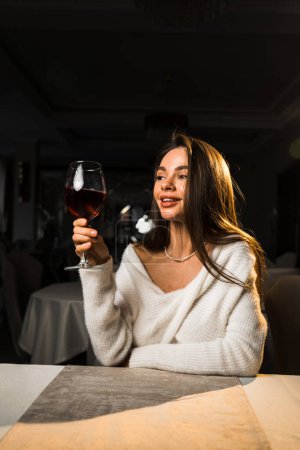 Young woman holding a glass of wine.Woman drinking wine in a restaurant.Red wine concept