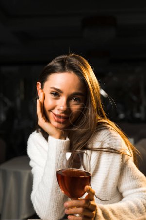 Mujer joven sosteniendo una copa de vino.Mujer bebiendo vino en un restaurante.Concepto de vino tinto