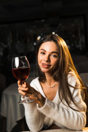Young woman holding a glass of wine.Woman drinking wine in a restaurant.Red wine concept