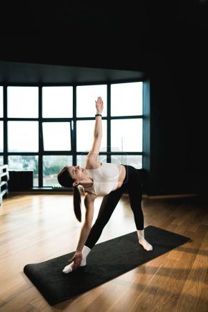 Jeune femme athlétique est engagée dans la forme physique et fait du yoga dans la gymnase. Yoga et fitness.