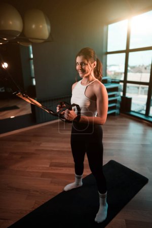 Photo for Beautiful woman doing exercise with trx system.Fitness exercises with loops.Concept workout healthy lifestyle sport. - Royalty Free Image
