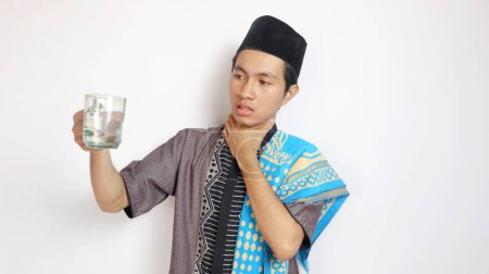 Hombre musulmán asiático está bebiendo porque tiene sed sobre un fondo blanco