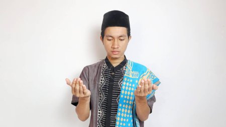 Asian Muslim man praying with both hands raised on a white background