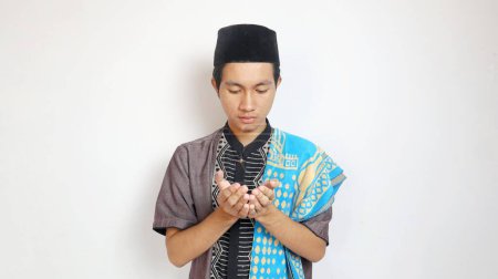 Hombre musulmán asiático rezando con ambas manos levantadas sobre un fondo blanco