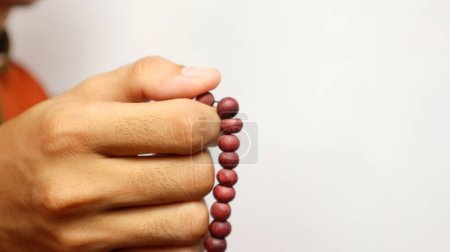 Asiatique musulman est tenant des perles de prière sur un fond blanc