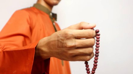 Asiatique musulman est tenant des perles de prière sur un fond blanc