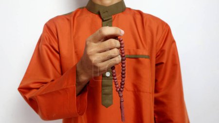 Asiatique musulman la main tient des perles de prière sur un fond blanc