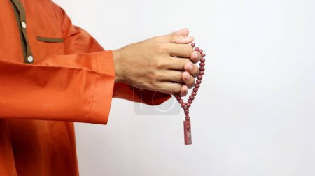 Asiatique musulman la main tient des perles de prière sur un fond blanc