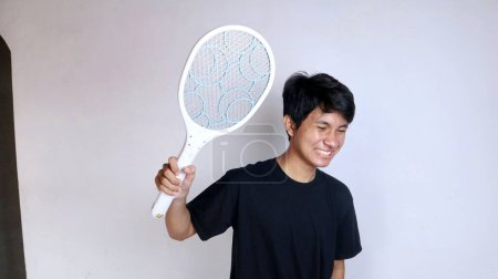 young Asian man using mosquito swatter, electric net racket on isolated white background