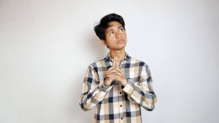 Thinking young Asian man posing looking up as if thinking about something or being confused about choosing with isolated white background