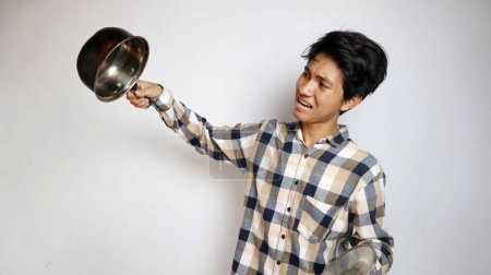 shocked young Asian man posing holding a pan on an isolated white background