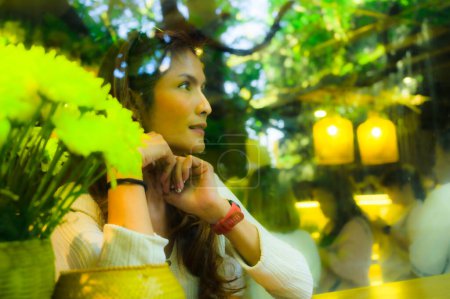 Asian woman looking through glass with comfortable atmosphere at a coffee shop in Chiang Mai Province, Thailand.