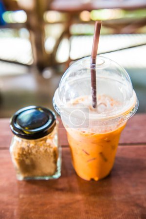 Iced Milk Tea with Sugar Jar on wooden Table, Thailand.