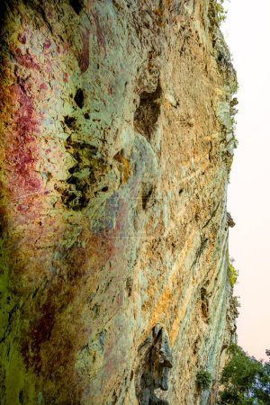 A large and unusually shaped cliff appears with ancient paintings on the rock walls at Pratu Pha archaeological site in Lampang province, Thailand.