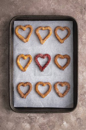 churros heart on a baking tray. High quality photo. baking tray with churros in a heart shape red one in centre