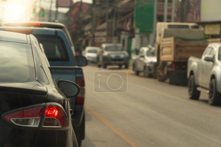 Photo for Rear side of black car with turn on brake light. Stop in line at an intersection with traffic lights on asphalt road. Various cars were lined up along the side of the city road. - Royalty Free Image