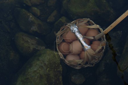 Eier in einem Korb in den heißen Quellen einweichen. Im Chae Son Nationalpark Thailand.