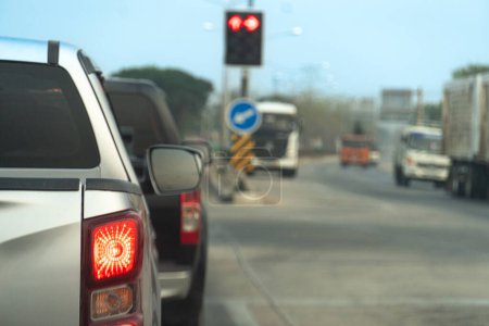Recogida de color plata coche en la parada de la carretera y encienda la luz de freno. Semáforo en la carretera. Imagen borrosa del atasco de tráfico.