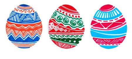 Foto de Un conjunto de huevos de Pascua llenos de adornos, de diferentes colores. Aislado sobre fondo blanco. Tres huevos. Colores azul, naranja, rojo, verde, rosa. Adorno geométrico, muchos detalles. garabato de color. - Imagen libre de derechos