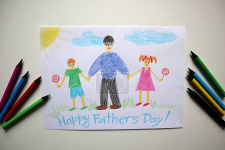 Foto de Una tarjeta del Día de los Padres dibujada por un niño. Fondo blanco. Lápices de colores cerca de la postal. La tarjeta muestra a un padre caminando con su hijo y su hija. Comen piruletas. Feliz Día de los Padres letras - Imagen libre de derechos
