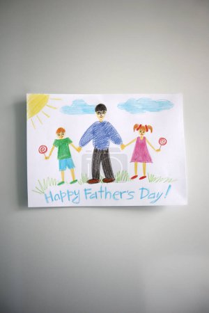 Foto de Una tarjeta del Día del Padre dibujada por un niño. Fondo blanco. La tarjeta muestra a un padre caminando con su hijo y su hija. Comen piruletas. Feliz Día del Padre. Dibujo con lápices de colores. - Imagen libre de derechos