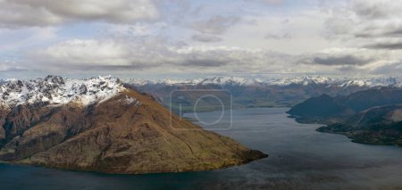 Photo for Breathtaking view of Lake Wakatipu with Fernhill, Queenstown nestled by its side, surrounded by majestic snow-capped mountains under a cloudy sky - Royalty Free Image