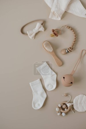 Téléchargez les photos : Elégant et élégant collage pour bébé et jouets sur fond beige pastel neutre. Bavoir en mousseline, sucette, chaussettes, arc, porte-sucette. Couché plat, vue du dessus - en image libre de droit