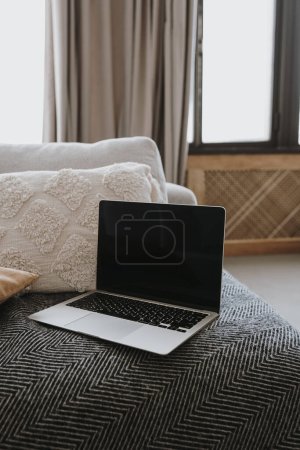 Téléchargez les photos : Ordinateur portable sur canapé avec oreillers. Travail à la maison, freelance, achats en ligne. Boutique en ligne, blog, image de marque des médias sociaux. Espace de travail à domicile esthétique - en image libre de droit