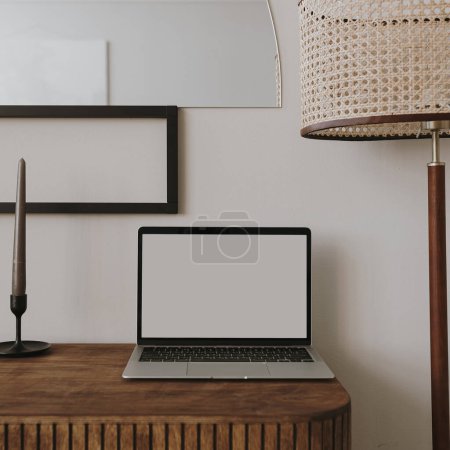 Laptop computer with blank screen on table with candles, floor lamp. Aesthetic boho styled home interior design template with mockup copy space. Online store, blog, social media, shop branding Poster 620992136