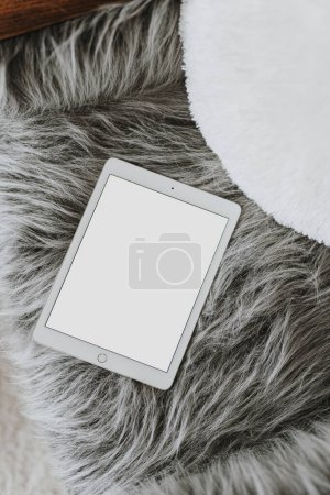 Flatlay tablet pad on fluffy woolen chair. Aesthetic elegant blog, social media, online store template with copy space