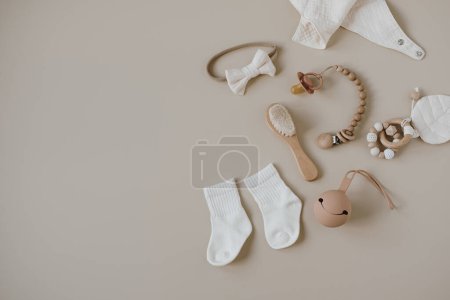 Téléchargez les photos : Pastel beige cosy eco friendly élégant scandinave accessoires de soins pour nouveau-nés. Boutique de mode en ligne, concept de marque de magasinage en ligne. Bavoir en mousseline, brosse, sucette, chaussettes, arc, porte-sucette - en image libre de droit